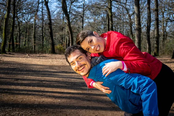 年轻夫妇在树林里做运动时玩得很开心 那个英俊的男人背着他的女朋友 — 图库照片