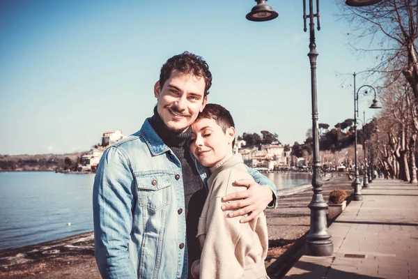 Genç çift Bracciano Gölü kıyısında yürüyor. İtalya 'nın Lazio kentindeki Anguillara Sabazia' ya seyahat eden güzel bir çift. Mesajınız için romantik atmosfer ve kopyalama alanı.