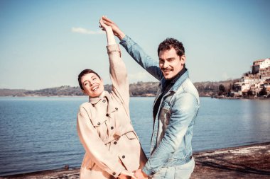 Genç bir çift Bracciano Gölü kıyısında dans eder ve eğlenir. İtalya 'nın Lazio kentindeki Anguillara Sabazia' ya seyahat eden güzel bir çift. Mesajınız için romantik atmosfer ve kopyalama alanı.