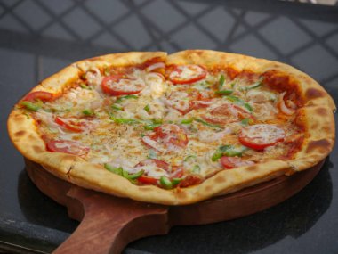 Hindistan 'da domates, kapsiyum ve soğanla kaplı vejetaryen peynirli pizza. Hint sebzeli pizza.