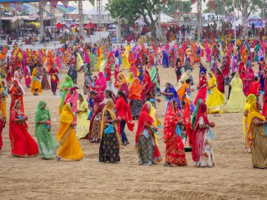 Puşkar, Rajasthan / Hindistan - 5 Kasım 2019: İtme karlı çölü stadyumunda dans gösterisi yapan köylü kadınlar Hindistan 'ın en büyük sığır ve kültür fuarı deve fuarında geleneksel elbiseleriyle dans ediyorlar.