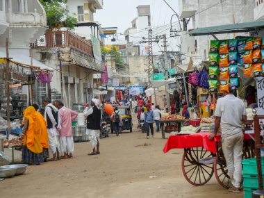 Pushkar, Rajasthan / Hindistan - 5 Kasım 2019: Hindistan kırsalındaki sokak pazarı. Hindistan 'ın Pushkar şehrindeki kırsal Hint kasabasında yürüyen kadın ve erkeklerle dolu kalabalık bir cadde.