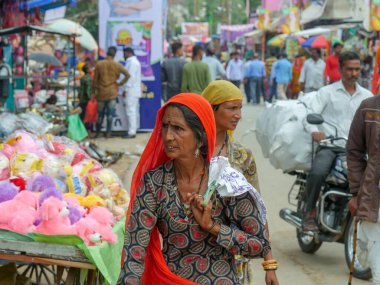 Pushkar, Rajasthan / Hindistan - 5 Kasım 2019: Hindistan kırsalındaki sokak pazarı. Hindistan 'ın Pushkar şehrindeki kırsal Hint kasabasında yürüyen kadın ve erkeklerle dolu kalabalık bir cadde.