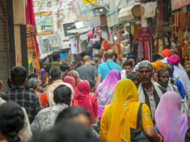 Pushkar, Rajasthan / Hindistan - 5 Kasım 2019: Hindistan kırsalındaki sokak pazarı. Hindistan 'ın Pushkar şehrindeki kırsal Hint kasabasında yürüyen kadın ve erkeklerle dolu kalabalık bir cadde.