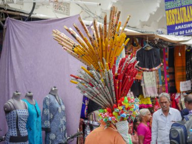 Pushkar, Rajasthan / Hindistan - 5 Kasım 2019: Meşgul sokak pazarında flüt satıcısı. Hindistan 'ın Pushkar şehrindeki kırsal Hint kasabasında yürüyen kadın ve erkeklerle dolu kalabalık bir cadde.