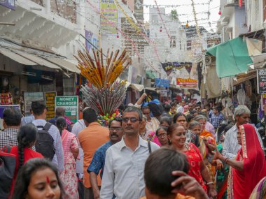 Pushkar, Rajasthan / Hindistan - 5 Kasım 2019: Meşgul sokak pazarında flüt satıcısı. Hindistan 'ın Pushkar şehrindeki kırsal Hint kasabasında yürüyen kadın ve erkeklerle dolu kalabalık bir cadde.