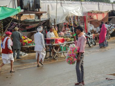 Pushkar, Rajasthan / Hindistan - 5 Kasım 2019: Hindistan kırsalındaki sokak pazarı. Hindistan 'ın Pushkar şehrindeki kırsal Hint kasabasında yürüyen kadın ve erkeklerle dolu kalabalık bir cadde.