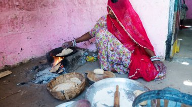 Bhinmal Rajasthan, Hindistan - 23 Mayıs 2017: Hint köy kadını geleneksel odun sobası üzerinde roti veya chapatti yemeği hazırlıyor.