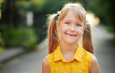 Dişsiz çocuklar gülümser. Küçük tatlı kız gülüyor, ilk süt dişini gösteriyor. Çocuk dişçiliği