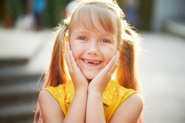 Dişsiz çocuksu gülümseme. Küçük tatlı kız gülüyor, ilk süt dişini gösteriyor. Çocuk dişçiliği. Komik surat.