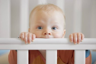 Komik bebek surat. İlk sütü olan ya da geçici dişleri olan küçük tatlı bebek bebek tahta beşik kemirir. Bebek, bebek odasında beşiğinde gülümsüyor.