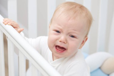 Küçük bebek beşiğinde ağlıyor, uyumak istiyor ve süt dişleri tırmanıyor. Pediatrik sorunlar