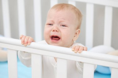 Küçük bebek beşiğinde ağlıyor, uyumak istiyor ve süt dişleri tırmanıyor. Pediatrik sorunlar