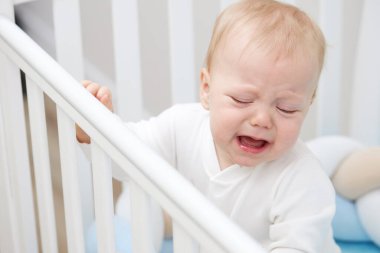 Küçük bebek beşiğinde ağlıyor, uyumak istiyor ve süt dişleri tırmanıyor. Pediatrik sorunlar