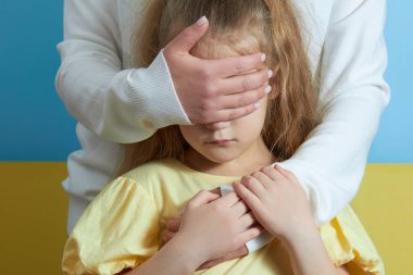 Ebeveyn elleriyle çocuğun gözlerini kapatır. Savaşı durdurun. Anne, Ukrayna 'da bir kızı savaştan koruyor.