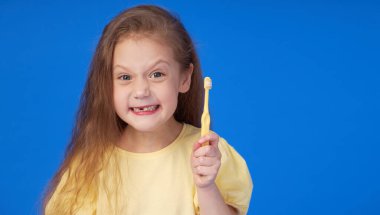 Dişsiz çocuk. Şirin küçük kız elinde diş fırçasıyla gülümsüyor. İlk süt dişi düştü. Pediatrik dişçilik ve diş hijyeni kavramı