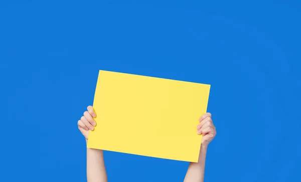 一个可爱的小女孩拿着一个黄色的标志在蓝色的背景上做题词 有趣的脸 — 图库照片