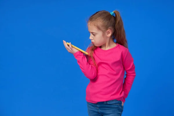 Słodka Dziewczyna Jasnoróżowym Swetrze Rozmawiająca Przez Telefon Komórkowy Niebieskim Tle — Zdjęcie stockowe