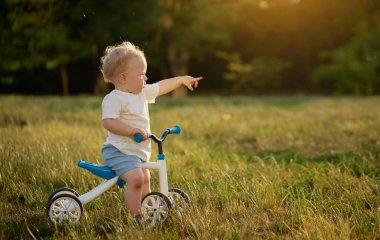 Sevimli bebek dengeli bisiklete binmeyi öğreniyor. Küçük bir çocuk güneşli bir parkta bisiklet sürmeye çalışır. Çocuk motosikletçi olmayı hayal ediyor.
