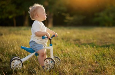 Sevimli bebek dengeli bisiklete binmeyi öğreniyor. Küçük bir çocuk güneşli bir parkta bisiklet sürmeye çalışır. Çocuk motosikletçi olmayı hayal ediyor.