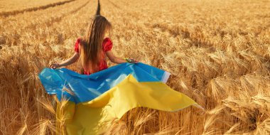 Gün batımında buğday tarlasında Ukrayna bayrağı taşıyan tatlı bir kız. Genç vatansever vatanını özlüyor ve zaferi bekliyor. Ukrayna için dua et.