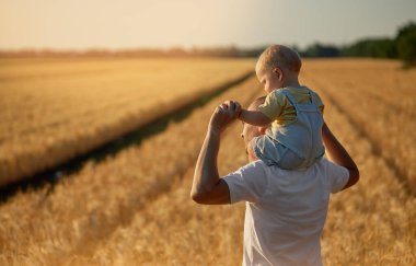Babalar günü. Baba ve küçük oğlu bir yaz sahasında birlikte oynuyorlar. Bebek babasının sırtına oturur.