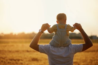 Babalar günü. Baba ve küçük oğlu bir yaz sahasında birlikte oynuyorlar. Bebek babasının sırtına oturur.
