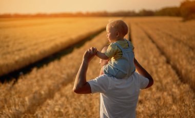 Babalar günü. Baba ve küçük oğlu bir yaz sahasında birlikte oynuyorlar. Bebek babasının sırtına oturur.