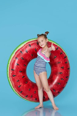 Mavi arka planda şişirilebilir karpuz şekilli şirin küçük kız. Komik çocuk yaz tatiline hazırlanıyor Komik çocuk 