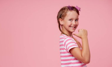 Portrait of surprised cute toddler girl child in star-shaped sunglasses over pink background. Points hands to the left side. Advertising childrens products