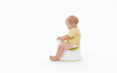 Bir bebeği tuvalet eğitimi. Tuvalet kağıdı rulosunun yanında oturan küçük çocuk ve beyaz bir arka planda bebek bezi.