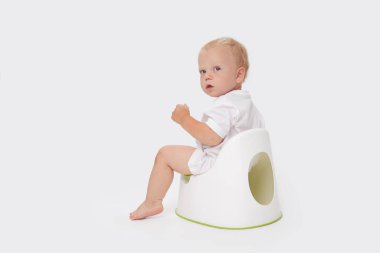 Bir bebeği tuvalet eğitimi. Tuvalet kağıdı rulosunun yanında oturan küçük çocuk ve beyaz bir arka planda bebek bezi.