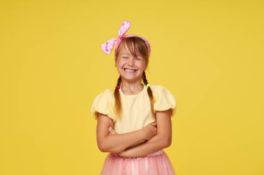 Sarı arka planda küçük şirin kız çocuğunun şaşırmış portresi. Kameraya bakıyorum. Ellerini yana doğru uzat. Çocuk ürünlerinin reklamını yapmak.