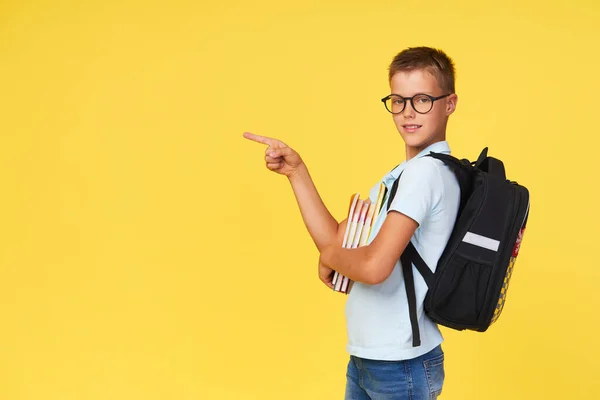 Portrait Schoolboy Glasses Textbooks Backpack Yellow Background Pointing Left Back — Stock fotografie