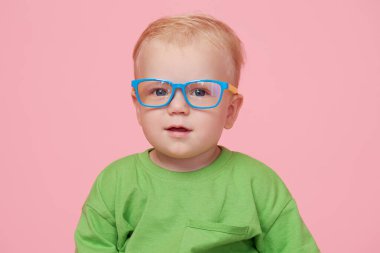 Pembe arka planda erkek bebek portresi gözlüklü ve kameraya bakıyor. Akıllı bebek konsepti