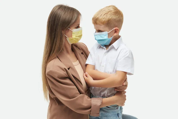 照顾所爱的人在Covid 19大流行病期间 年轻的母亲抱着戴着防护口罩的小儿子 工作室白色背景 — 图库照片
