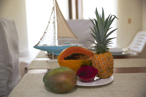 Fresh exotic fruits on a wooden table with napkins, yacht model and window