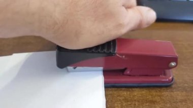 Beyaz zemin üzerinde el, kalem ve zımba yakın plan