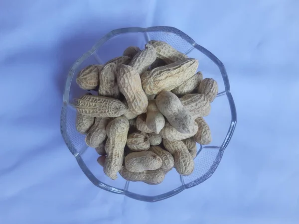 Roasted peanuts are placed on glass bowl.