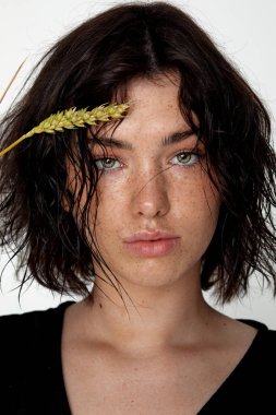beauty young woman face with a lot of freckles and natural lips, wheat  near face, close up, thicker eyebrows
