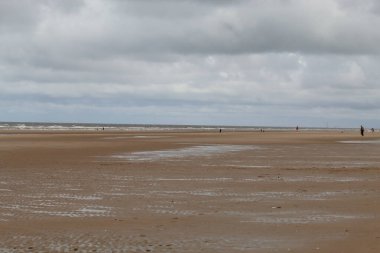 Merseyside, Liverpool 'daki Formby Sahili' nde güzel bir manzara çekimi. Bu plaj Pine Woods 'a yakın, sadece kum tepeleriyle ayrılmış. Her ne kadar bir yaz sabahı çekilmiş olsa da, bu fotoğrafın üzerinde kediler ve bulutlu bir gökyüzü var..