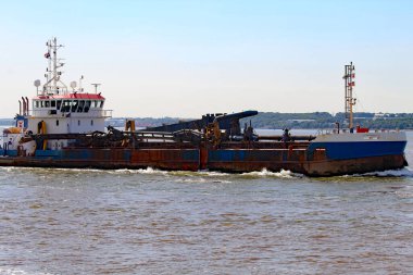 A boat travelling along the River Mersey on a warm summer afternoon. Cheshire and The Wirral can be seen in the background of the image. This was taken on a clear afternoon.