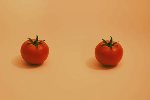 Zwei Rote Isolierte Tomaten Mit Grünen Blättern Auf Orangefarbenem Hintergrund — Stockfoto