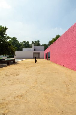 Luis Barragan 'ın mimari işleri, siyah giyinmiş çocuk, kum üzerinde, pembe Meksika duvarı, sırt çantası, ağaçlar, fıskiyeler, bağlamdaki su aynası..
