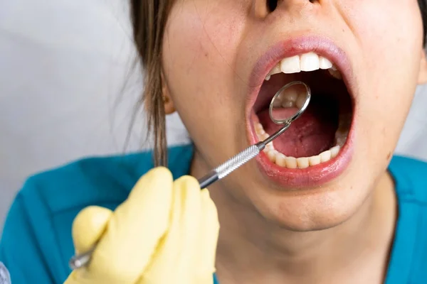 young female dentist holding dental instruments in her hand, protected by a glove on a white background and wearing a mouth cover.