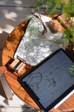 furniture design, digital drawing in tablet and analog in notebook, hand drawing, proposal of design of armchair, furniture, with samples of fabric and wood that it would have