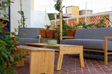 Patio. Garden. Urban, neutral, outdoor living space. Exterior photo. Outdoor living room with couch, comfy cushions, throw pillows, love seat, chairs and coffee table. Backyard with greenery, plants.