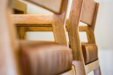 designer chair, solid wood seat in fabric or natural leather, oak wood, pink purple. black background with natural stones on the floor