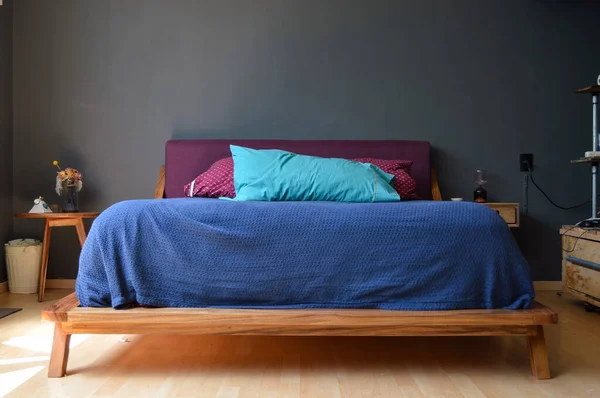 bed base, bedroom with mat on the floor, clay pot in the background, wooden credenza and mirror. The same wooden floor, cozy, modern space, with style and design.