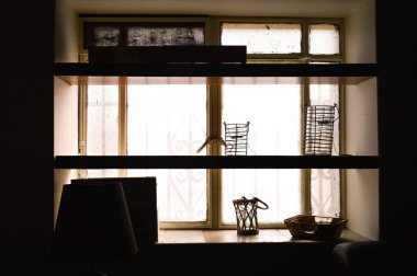 wooden shelves against the light, with decorative objects on the shelves. Light in contrast to natural lighting from the window